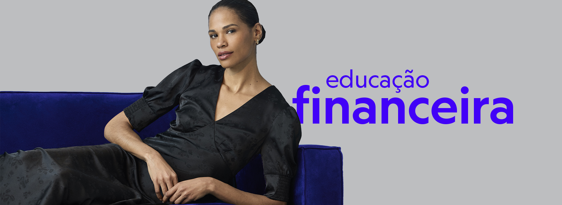 Em um fundo cinza, uma modelo veste um vestido preto de mangas bufantes e posa reclinada em um sofá azul. Ela apoia o braço sobre o encosto enquanto olha em direção à câmera. À sua direita, lê-se “educação financeira” em destaque.