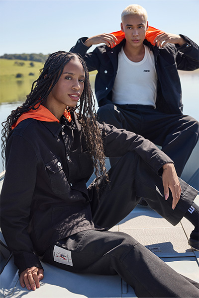 Dois modelos, um homem e uma mulher, vestem as peças da collab C&A e PACE: regata branca, calça preta e jaqueta preta com capuz laranja.