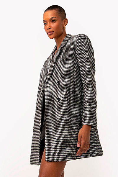 Modelo veste casaco longo quadriculado com padronagem pequena em preto e branco
