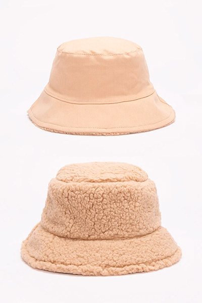Foto mostra dois bucket hats: acima, um todo bege, de sarja. Abaixo, um também bege, em tonalidade mais escura, de sherpa