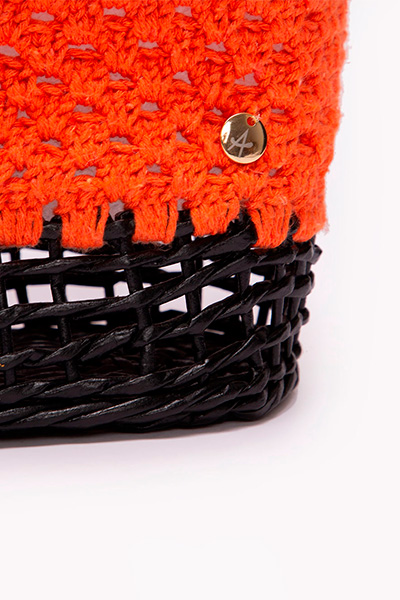 Detalhe da bolsa de crochê laranja com a parte de baixo preta. Peça foi feita em parceria com a marca Casa de Maria e faz parte da coleção Nosso Encontro 2023