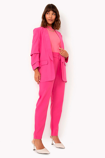 Modelo veste blazer de alfaiataria alongado com manga drapeada pink, calça de alfaiataria pink e sapato off white