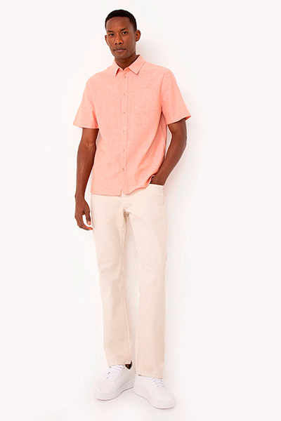 Modelo veste camisa rosa de manga curta, calça wide leg off white e tênis branco