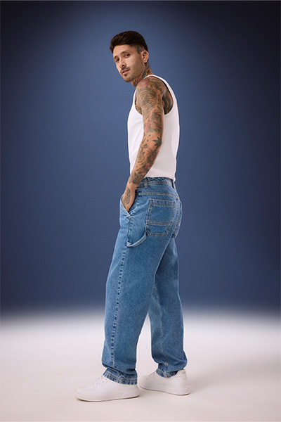 Modelo veste calça jeans wide leg masculina de lavagem azul e regata branca