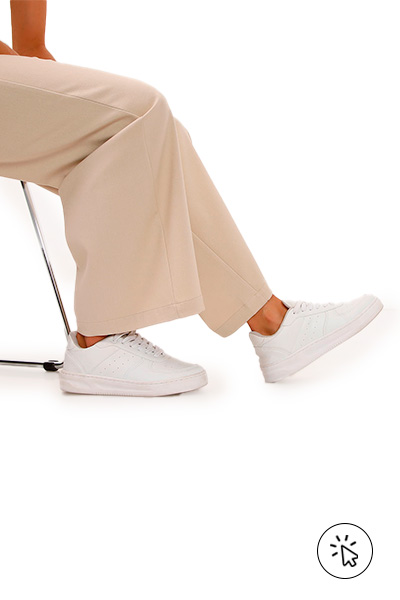 A imagem é somente do pé da modelo, que usa uma calça pantalona bege e um tênis casual off white. - 7 estilos universais - quais são os 7 estilos universais - quem criou os 7 estilos universais - estilo casual - estilo esportivo