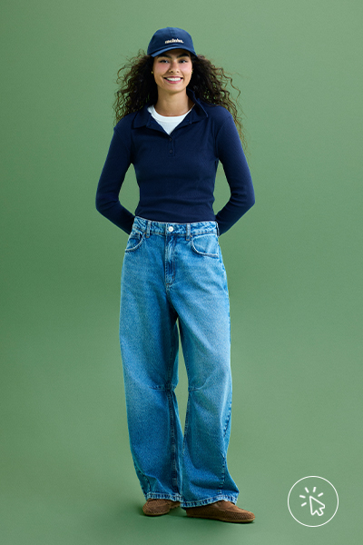 Modelo veste boné azul marinho, suéter de tricô feminino com gola esportiva azul marinho e calça jeans wide leg