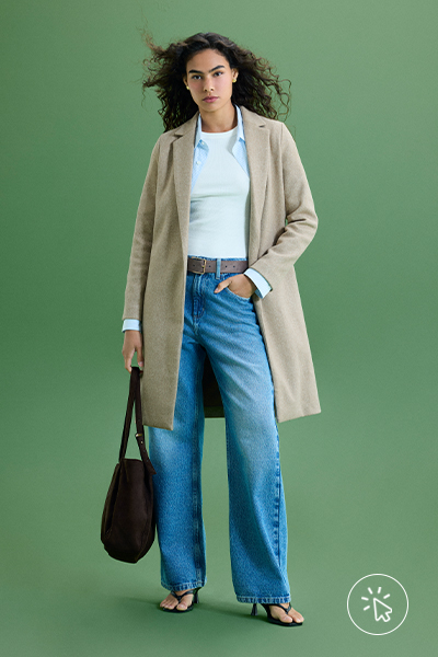 Modelo veste camiseta branca, camisa azul feminina aberta, casaco alongado bege e calça jeans