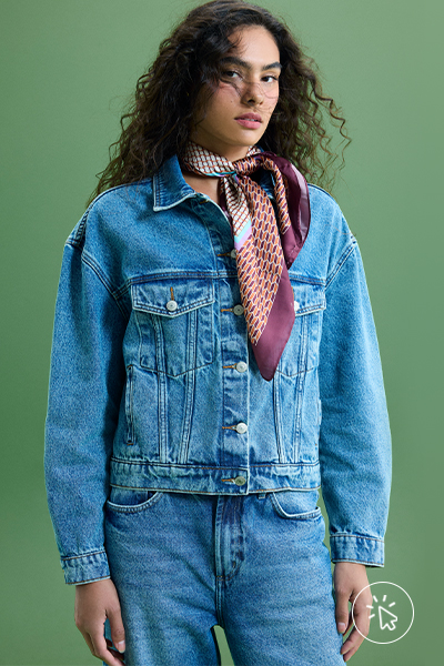 Modelo veste jaqueta jeans feminina, calça jeans e lenço estampado bege e vinho no pescoço