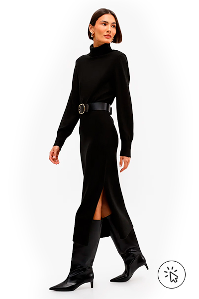 A modelo está usando um vestido de tricô preto, com gola alta, manga longa e fenda. Nos pés, uma bota de cano alto - o que dar de presente de dia das mães - o que comprar para o dia das mães - roupa para o dia das mães