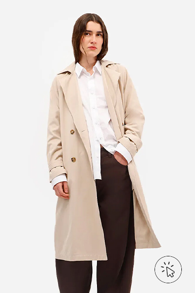 Modelo veste trench coat bege, camisa feminina branca e calça barrel feminina de sarja marrom