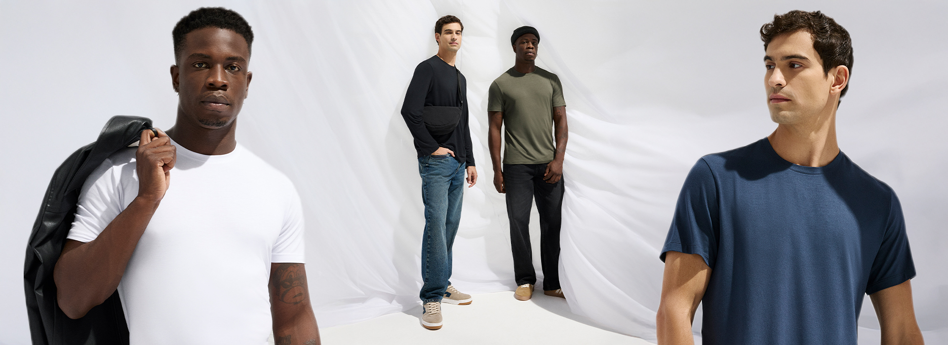 O fundo da imagem é um pano branco em movimento. O modelo da esquerda está usando uma blusa de manga longa preta e calça jeans, o modelo da esquerda está usando uma camiseta verde e uma calça preta