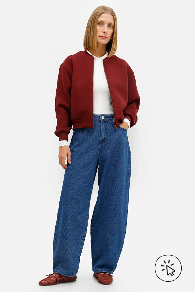 Modelo veste jaqueta bomber vinho, camiseta branca e calca balloon feminina jeans listrada azul