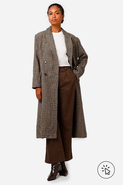 Modelo veste trench coat bege pied de poule, calça de alfaiataria marrom e botas