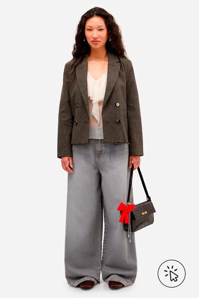 Modelo veste blazer de alfaitaria xadrez marrom e calça jeans baggy cinza