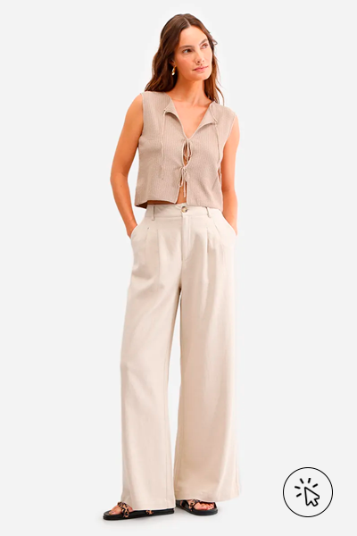 Modelo veste regata de tricô com amarração bege e calça pantalona com linho bege