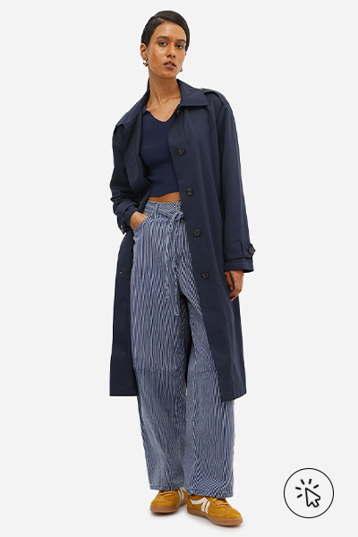 Modelo veste casaco alongado azul marinho e calça baggy balloon feminina jeans listrada com cordão azul