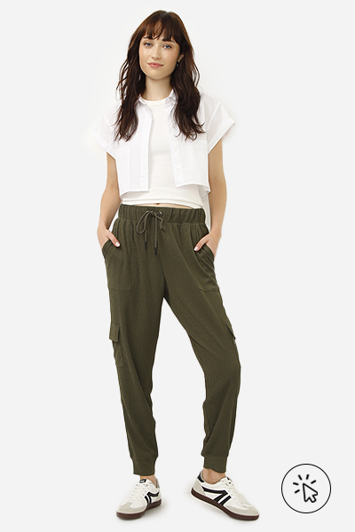 Modelo veste regata branca com camisa cropped por cima e calça jogger cargo texturizada com bolsos utilitários