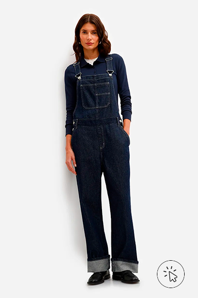 Modelo veste jardineira longa feminina jeans azul escuro com camiseta manga longa preta por baixo