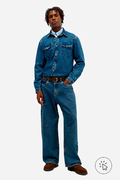 Modelo veste camisa masculina azul clara, camisa jeans oversized por cima e calça super baggy masculina jeans azul