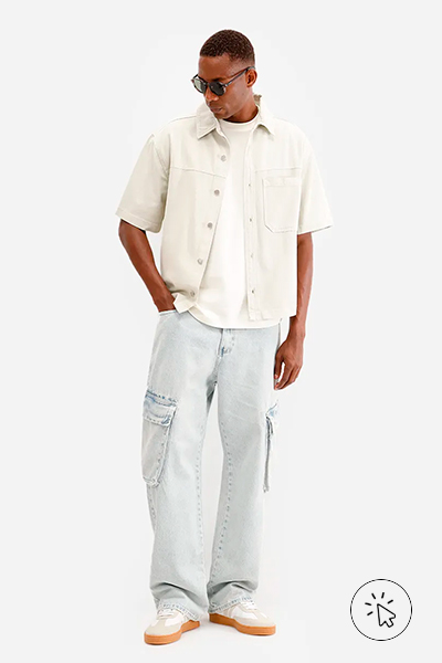 Modelo veste camiseta branca, camisa masculina de sarja manga curta areia e calça cargo cinza claro