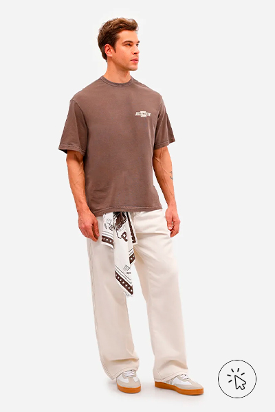 Modelo veste camiseta masculina de algodão Chevrolet Opala Marrom, calça off-white e tênis off-white