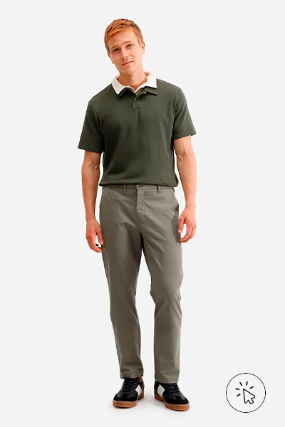 Modelo veste sobreposição de duas polos – bege por baixo e verde musgo por cima –, calça cinza e tênis preto