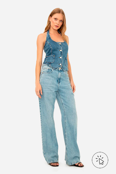 Modelo veste colete jean com botões azul e calça reta jeans azul um tom mais claro