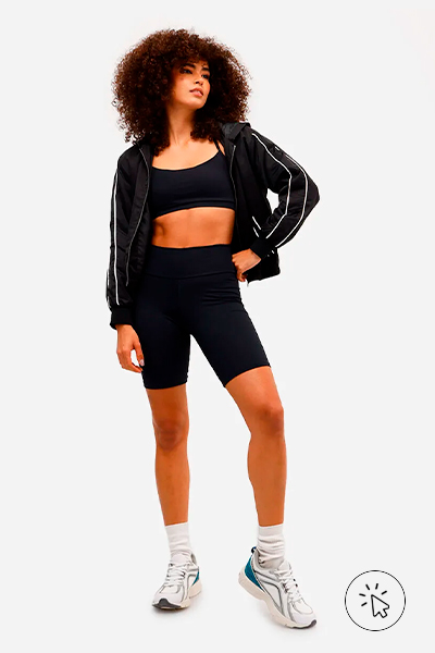 Modelo veste top esportivo preto, bermuda biker feminina esportiva ACE e casaco corta-vento preto por cima