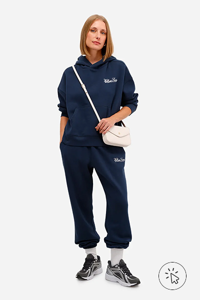 Modelo veste blusão de moletom azul marinho, calça jogger azul marinho, meias brancas, tênis esportivo e bolsa compacta clara - look comfy para show de trap - o que é comfy