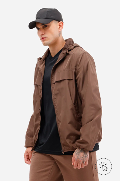 Modelo veste boné preto, jaqueta corta vento com capuz marrom, camiseta preta e bermuda de moletom marrom - look comfy para show de trap - o que é comfy