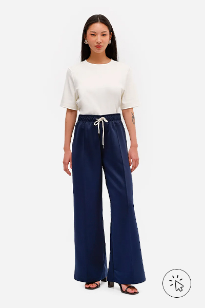 Modelo veste camiseta feminina de algodão peruano oversized com recorte off-white e calça flare azul marinho