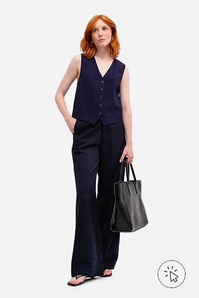 Modelo veste colete feminino de alfaiataria em viscose e calça de alfaiataria wide leg, ambas as peças azul marinho