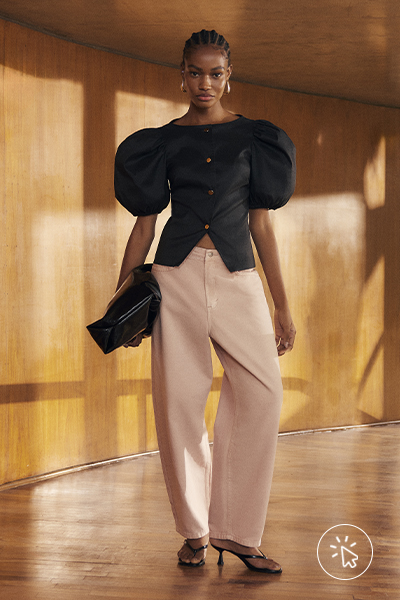 Modelo veste blusa preta com mangas bufantes e calça balloon rosa pastel