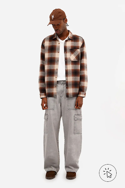 O modelo está usando calça cargo jeans, camiseta branca e camisa xadrez marrom por cima. - o que combina com calça jeans clara masculina - como usar calça jeans clara masculina