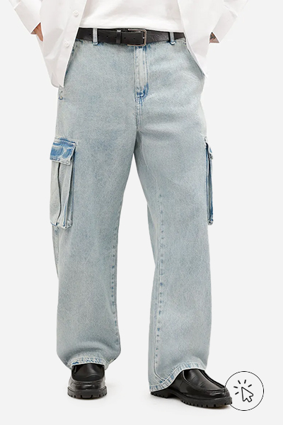 A foto está focada na cintura pra baixo do modelo, que está usando jeans claro cargo e tênis casual. - o que combina com calça jeans clara masculina - como usar calça jeans clara masculina