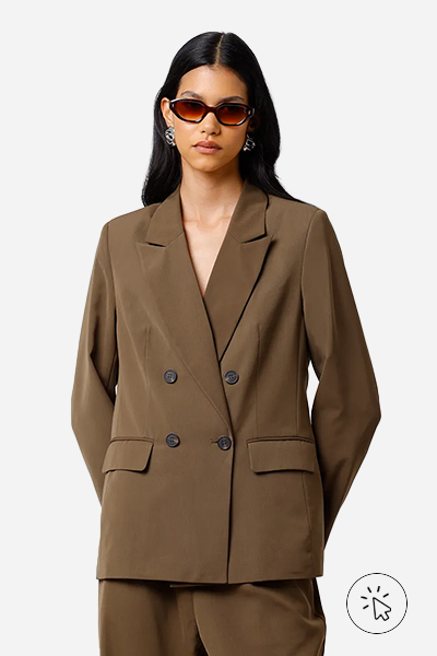 Modelo veste blazer marrom de abotoamento duplo, calça de alfaiataria marrom combinando, óculos de sol e brincos prateados - roupas anos 80 - look anos 80 - moda anos 80 - como era a moda nos anos 80