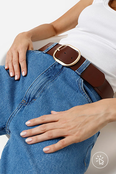 Modelo veste regata branca, calça jeans azul e cinto largo marrom com fivela dourada oval - roupas anos 80 - look anos 80 - moda anos 80 - como era a moda nos anos 80