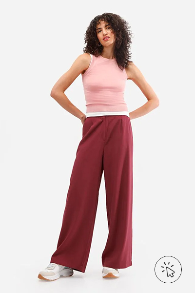 Modelo veste regata rosa clara, calça wide leg de alfaiataria vinho e tênis branco com detalhes bege - roupas anos 80 - look anos 80 - moda anos 80 - como era a moda nos anos 80