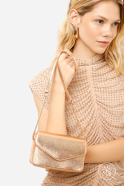 Modelo segurando bolsa tiracolo texturizada metalizada dourada - roupas anos 80 - look anos 80 - moda anos 80 - como era a moda nos anos 80