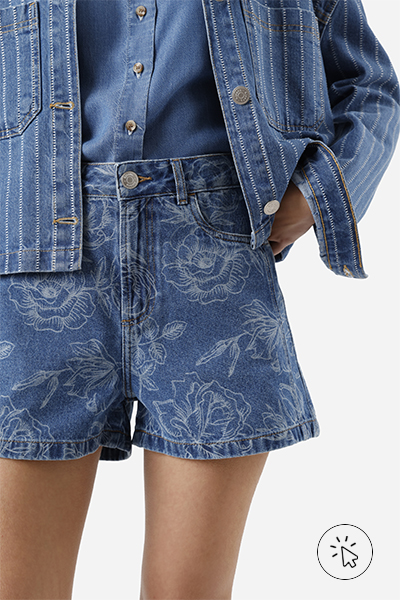 Modelo veste look all jeans com jaqueta listrada oversized e camisa soltinha por dentro do short com estampa floral - história do jeans - como surgiu o jeans - como é feito o tecido jeans - tipos de jeans tecido - modelagens de jeans 