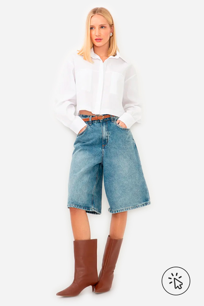 Modelo veste camisa cropped manga longa com bolsos off-white, jorts jeans azul médio e bota cano alto marrom caramelo