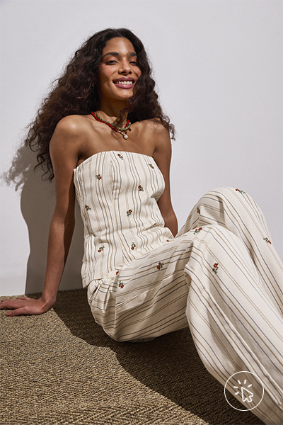 Modelo veste calça wide leg slim feminina de sarja com bordado floral listrada off-white e blusa sem alças na mesma estampa