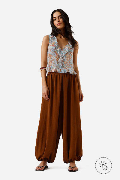 Modelo veste blusa feminina de lurex e babados floral colorida e calça aladim marrom