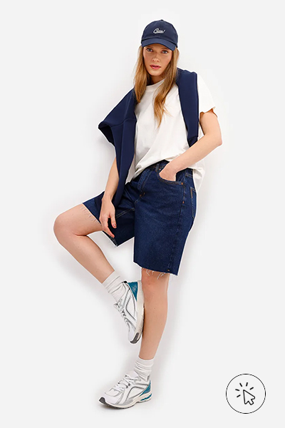 Modelo veste bermuda feminina jeans cintura alta barra a fio azul escuro