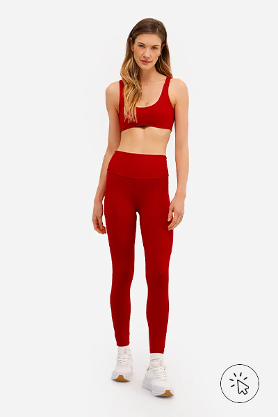Modelo veste top feminino esportivo ACE vermelho escuro e calça legging do mesmo tecido e cor
