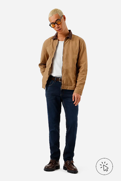 Modelo veste calça skinny masculina jeans azul escuro e jaqueta bege com gola marrom - cores que combinam com azul