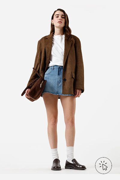 Modelo veste minissaia feminina jeans cintura média azul e blazer marrom - cores que combinam com azul