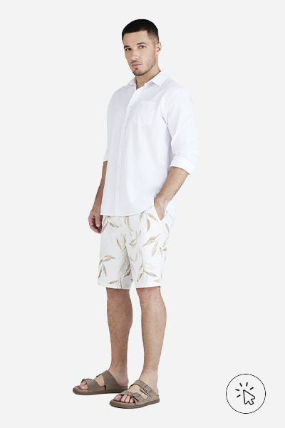Modelo veste bermuda masculina off-white com estampa folhagens e camisa manga longa branca