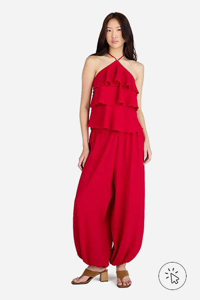 Modelo veste blusa sem mangas com babados vermelha e calça balloon feminina texturizada na mesma cor