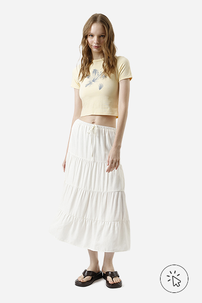 Modelo veste camiseta baby tee amarelo manteiga e saia mídi com babados off-white